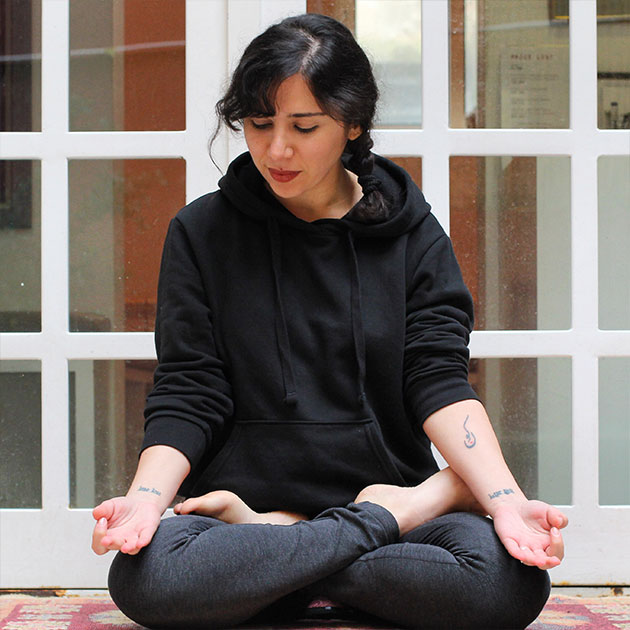 Sandy Boutros wearing black clothes, meditating