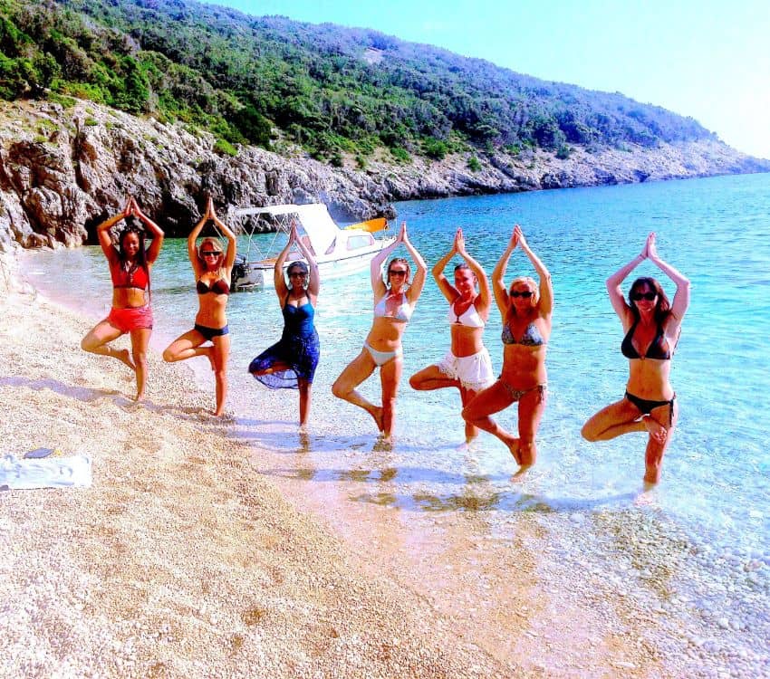 Yoga students in tree pose on the beach at Himalaya Yoga Insitute in Spain