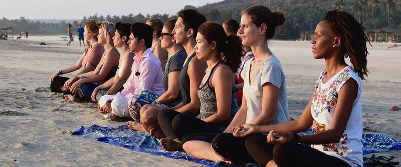 Yoga teacher training students sit on the beach in Goa, India during a training course.