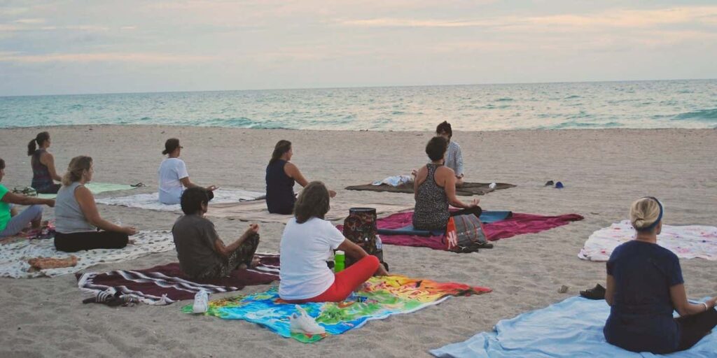 Yoga students on the beach being taught by a yoga instructor in Goa, India during a yoga teacher training