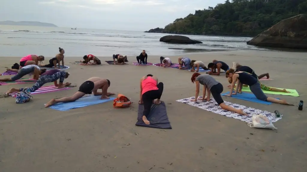 Yoga students practicing in a circle on the beach