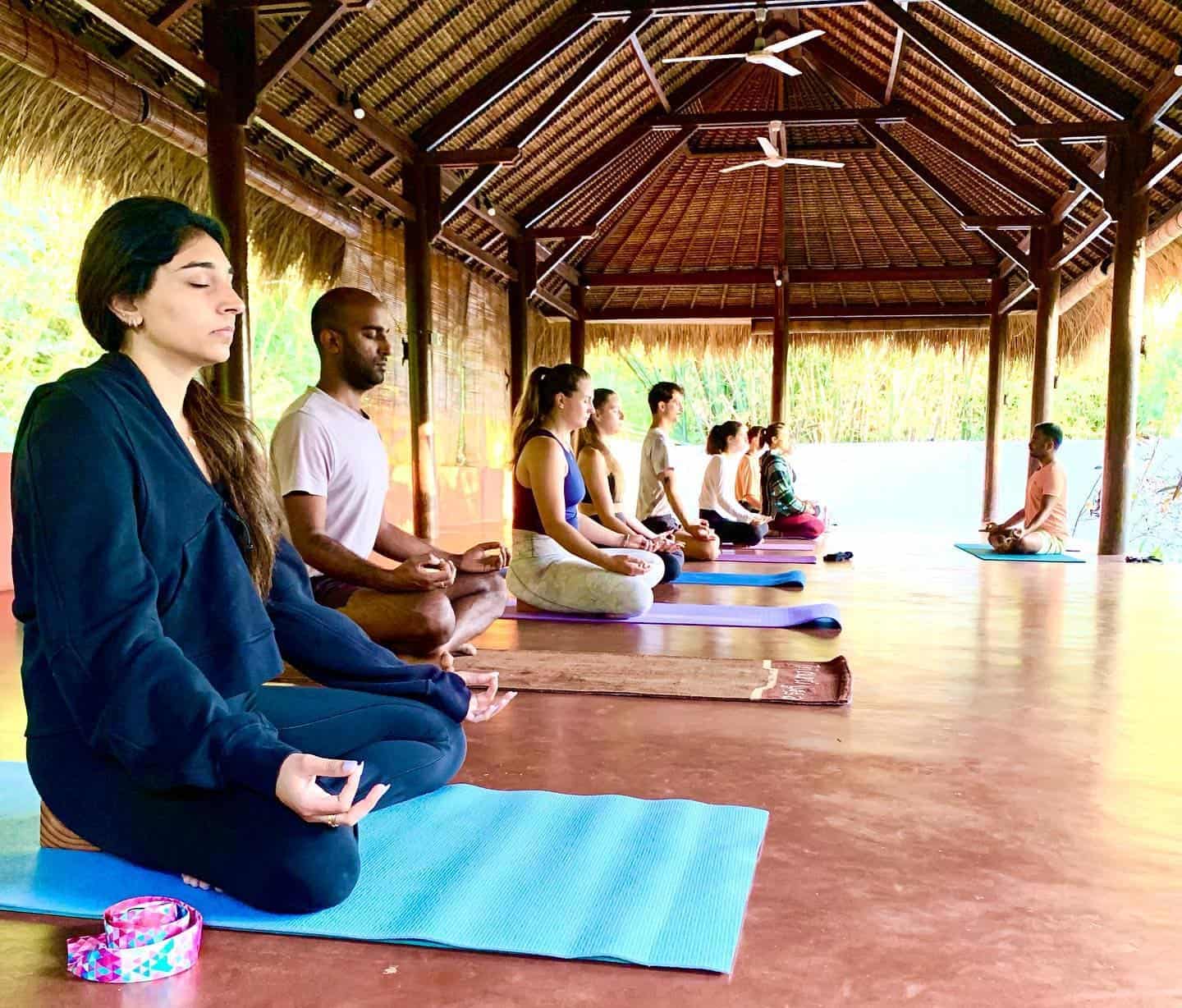 yoga teacher with yoga students in meditation in Goa, India