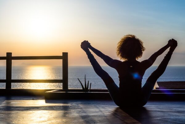 Joanna the co-founder of Alpha Yoga School as she takes upavista konasana b facing the ocean as the sun sets.