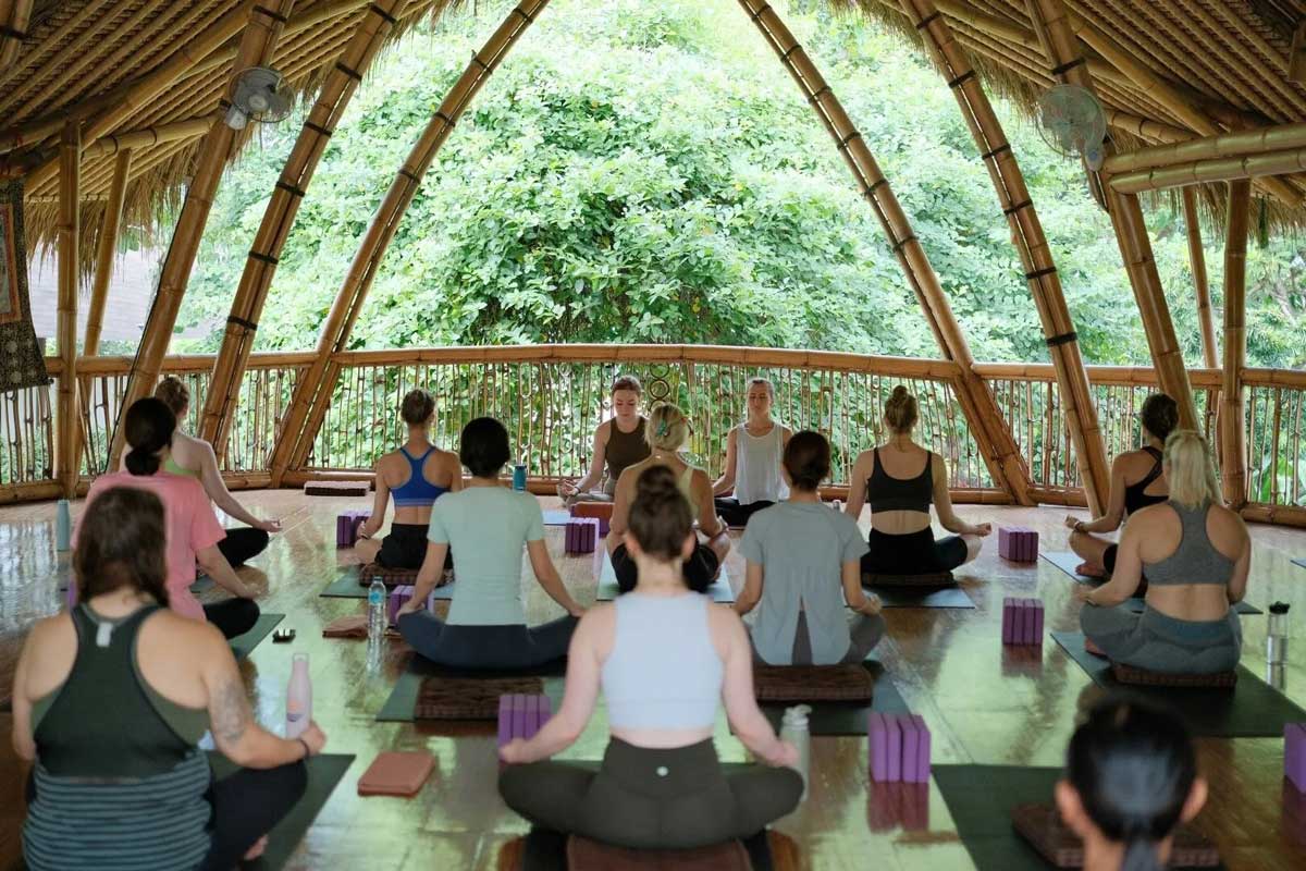 Yoga students in a beautiful shala as they meditate with their teachers during yoga teacher training in Bali.