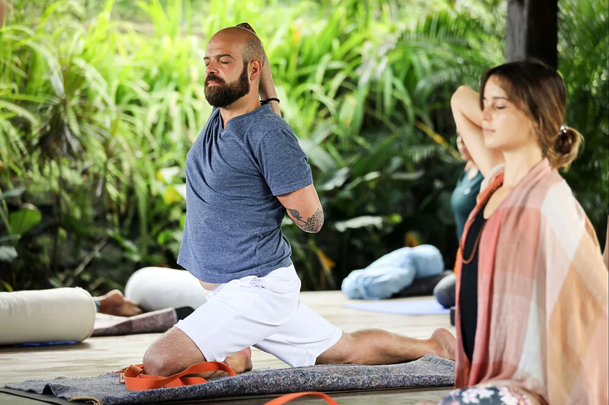 Yoga students practicing asana with gomukhasana arms in the shala during their yoga teacher training in Bali.
